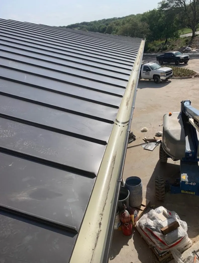 Standing seam panel and gutter detail on a metal roofing jobsite in Cave Springs